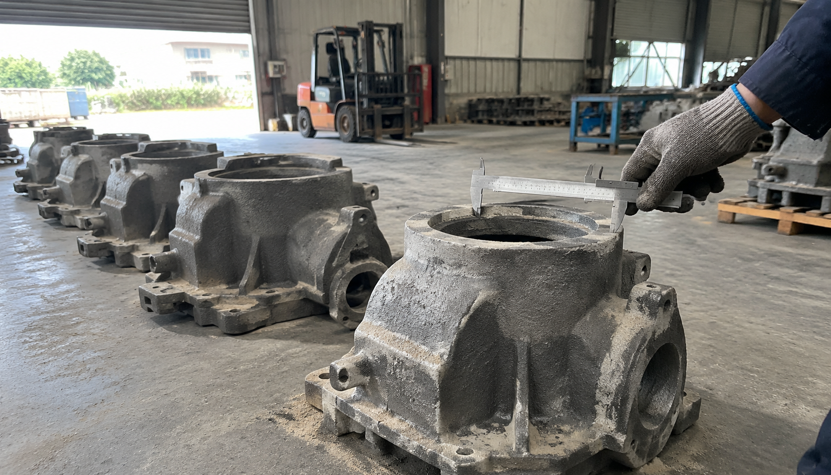 Gray iron castings laid out on a foundry floor being measured