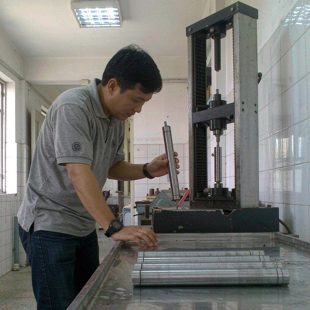 Technician holding a machined tensile test bar in a foundry lab